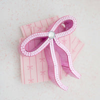 Stacked display of petal pink bow napkins styled with a pink bow decoration.