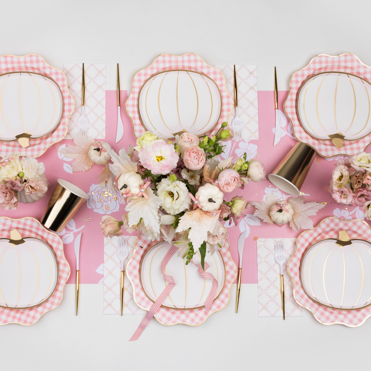 Pink gingham dinner plates styled on event table with coordinating décor.