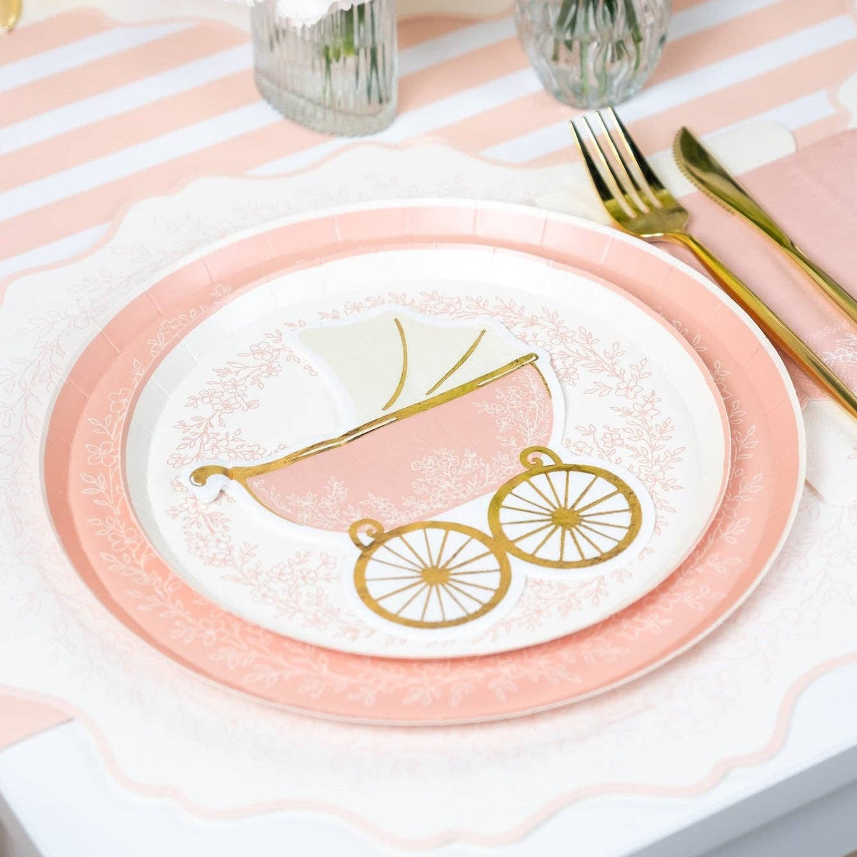 pink baby carriage napkin styled on table setting with plates and gold cutlery
