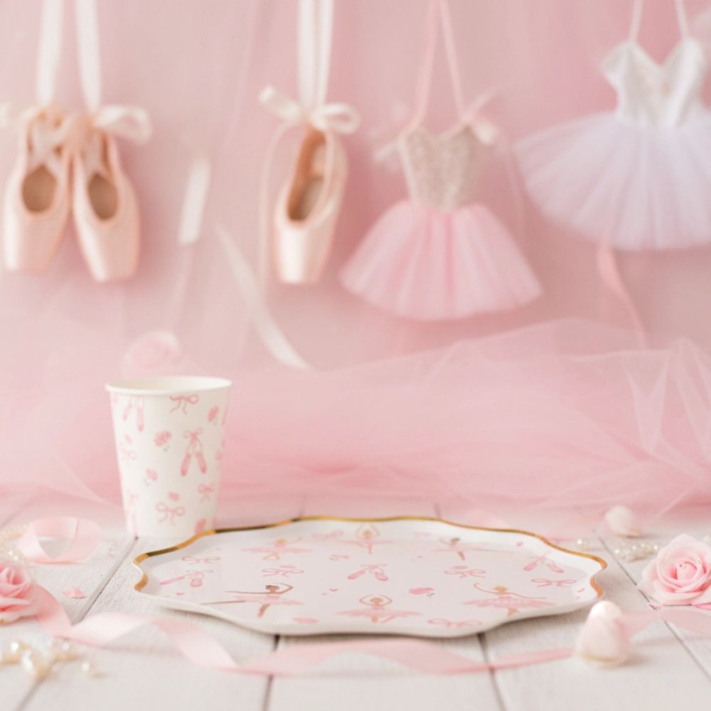 Ballerina plate and cup on a wooden table with pink tulle and ballet slippers