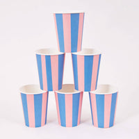 Six pink and blue cabana stripe paper party cups stacked in a pyramid on a white background.