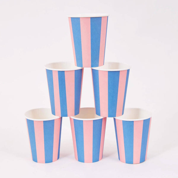 Six pink and blue cabana stripe paper party cups stacked in a pyramid on a white background.