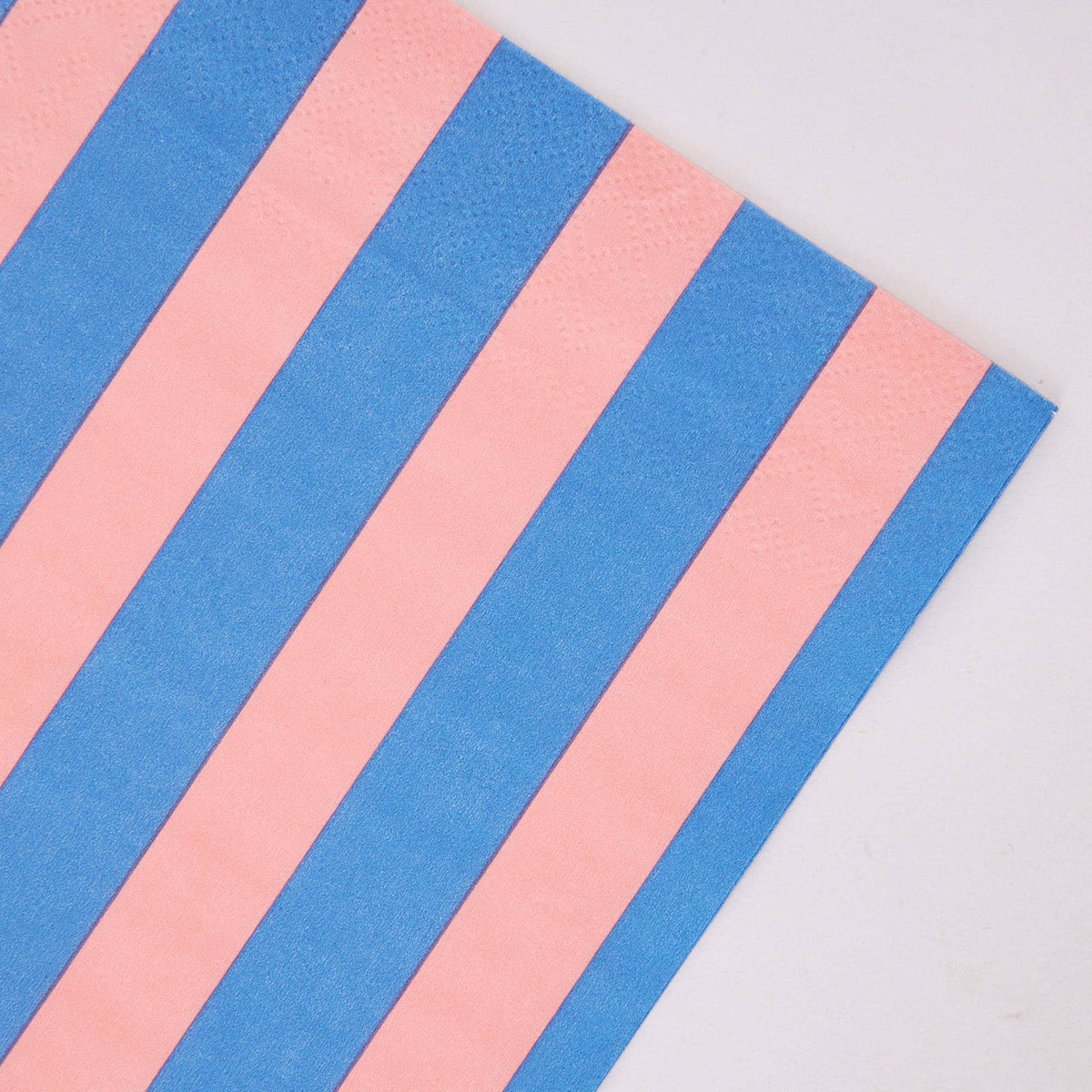 Angled corner detail of pink and blue striped paper napkin