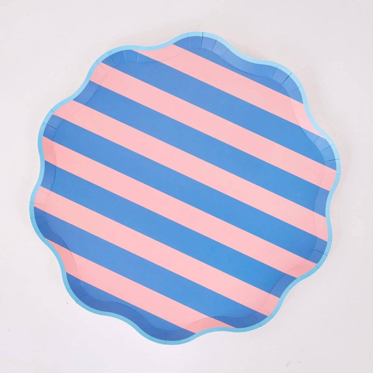 Pink and blue diagonal cabana stripe paper dinner plate with a wavy scalloped edge and light blue border, on a white background.