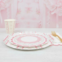 Place setting with stacked pink plates and a gold fork on white wood