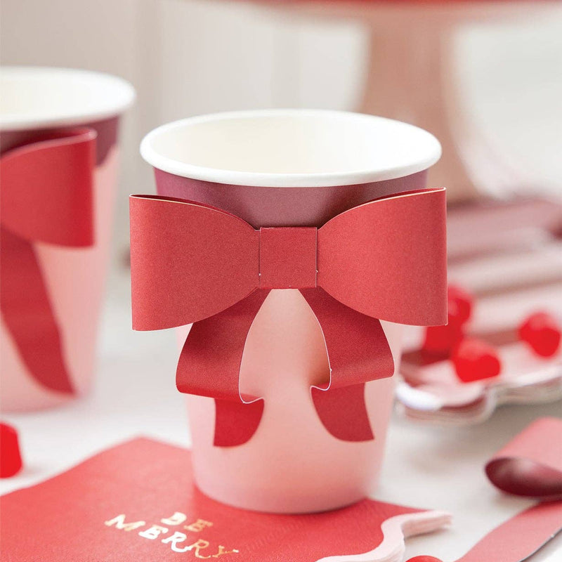 Close-up of pink and burgundy cup with bow surrounded by red holiday candies
