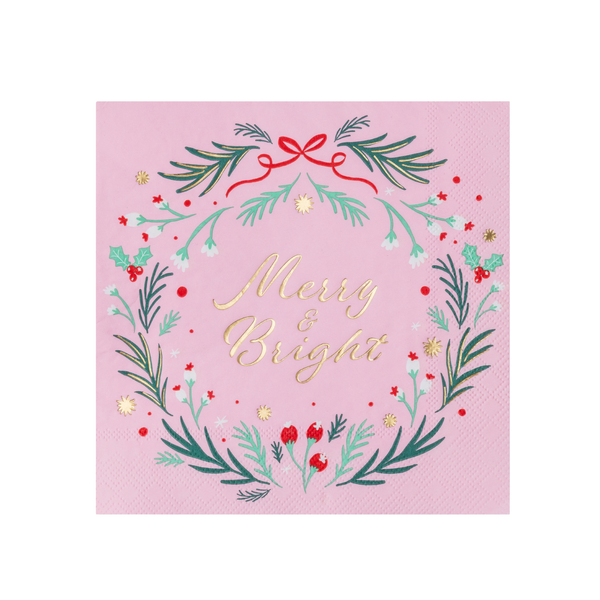 Flat pink Christmas napkin with a green wreath, red berries and a red bow circling gold "Merry & Bright" script on a blush ground.