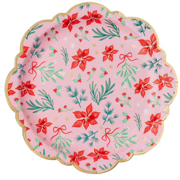 Soft-pink Christmas dinner plate with red winter florals, green sprigs, red bows, gold accents, and a swan, finished with a gold-trimmed scalloped rim, overhead view on white background.