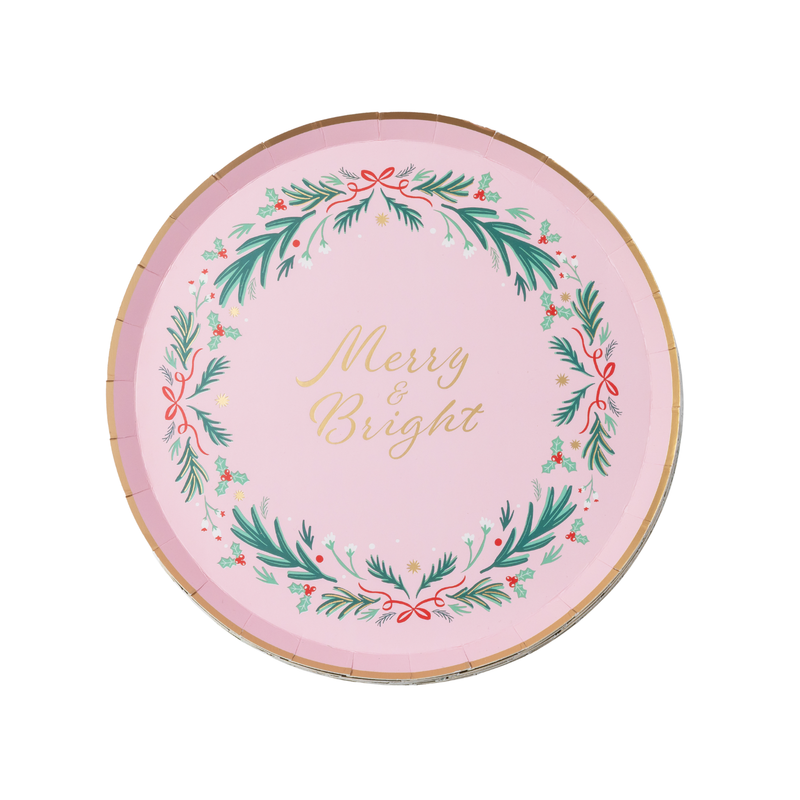 Flat blush-pink Christmas plate with a green berry wreath circling gold "Merry & Bright" script and a thin gold rim.