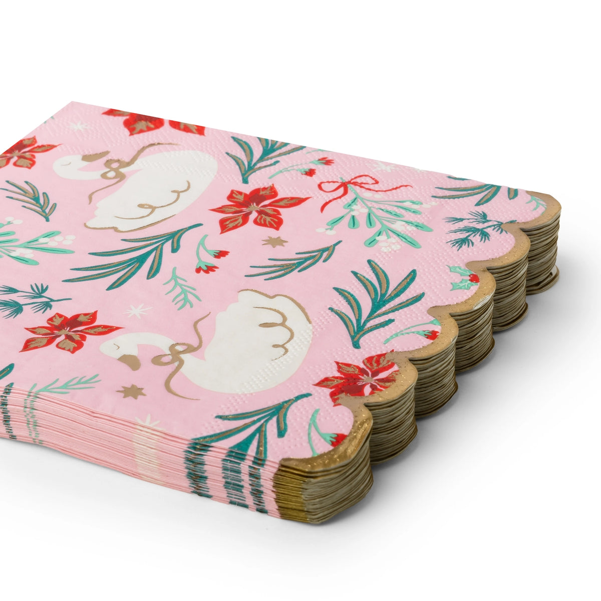 Stack of folded pink swan Christmas paper napkins showing the floral print and gold scalloped edge from an angle.