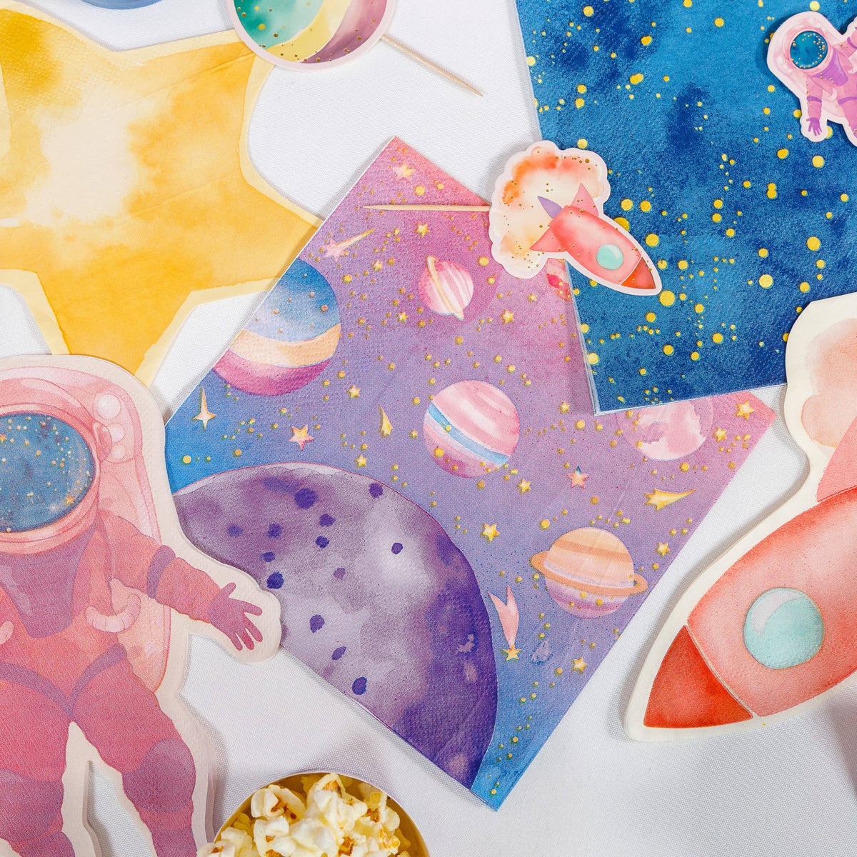 Pink space party spread with galaxy napkins, star-shaped napkins, astronaut and rocket cutouts