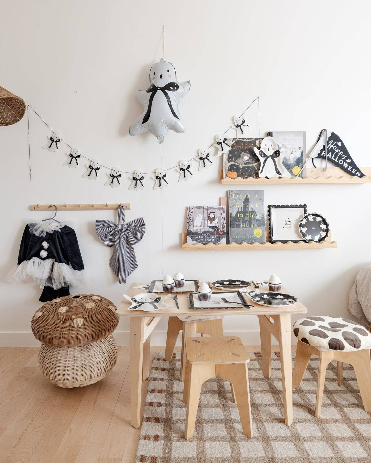 Children's room with Halloween decorations of Happy Halloween felt pennant on a table setting, shelves, and stools.