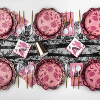 Pink and burgundy Halloween tablescape with gold-spiderweb floral plates, "Haunt Me" scalloped napkins, gold cutlery, gold cups, and a black lace runner.