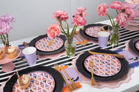Wide overhead of the full pink Halloween table — multiple witch hat plates on black chargers, black-and-white striped runner, pink roses, purple napkins, and gold flatware.