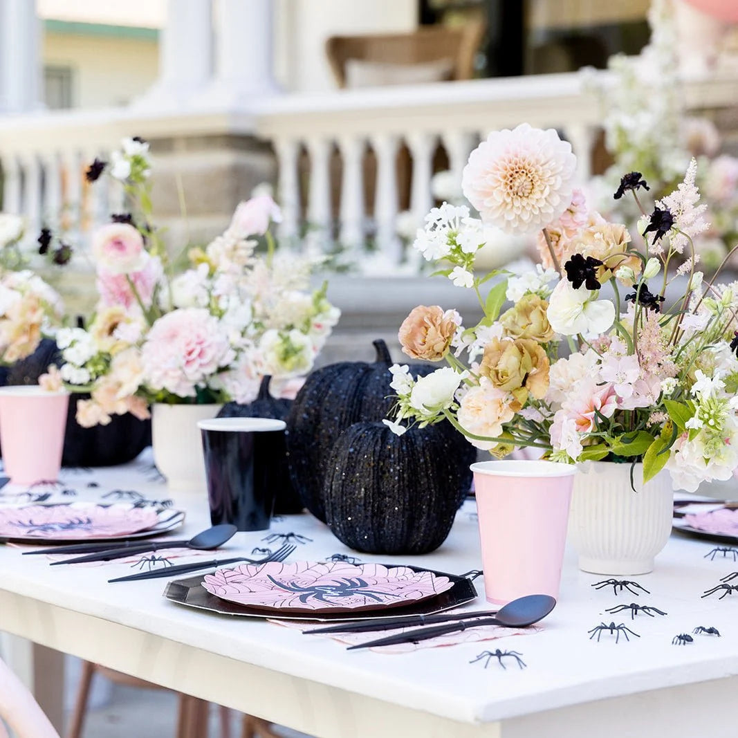 Elegant pink Halloween tablescape with the scalloped plates, black pumpkins, and blush floral centerpieces.
