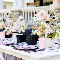 Elegant pink Halloween tablescape with the scalloped plates, black pumpkins, and blush floral centerpieces.