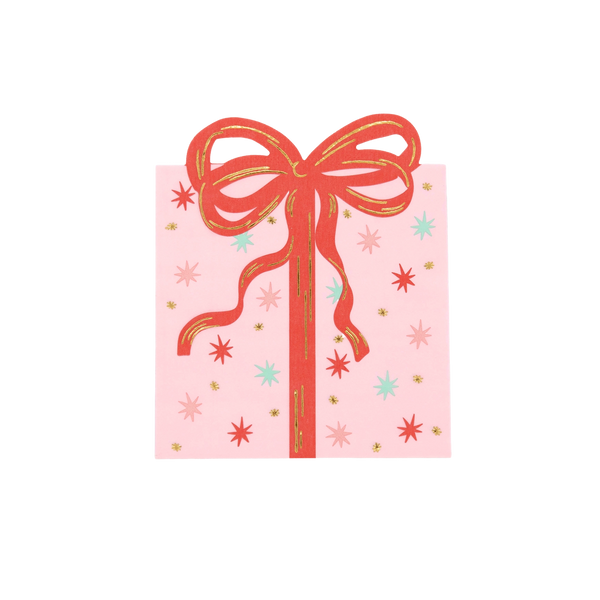 Top-down studio view of a square pink paper napkin designed to look like a Christmas present with a red bow and gold foil stars.