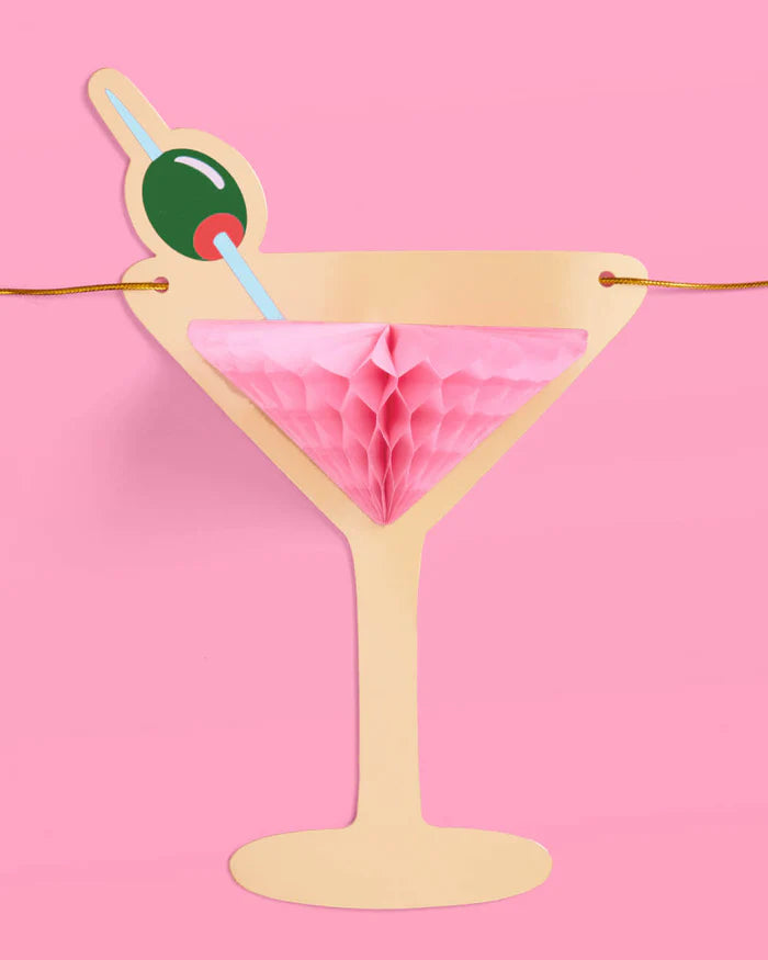 Close-up of single pink martini glass banner piece with pink honeycomb tissue and green olive detail