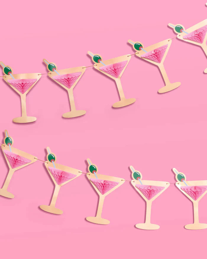 Two rows of pink martini glass banners with gold foil silhouettes and pink tissue accordions against pink background