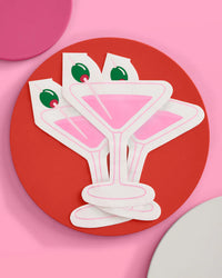 Stack of three pink martini shaped cocktail napkins fanned on a red plate