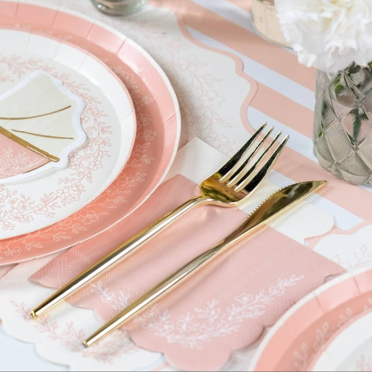 Close-up of pink floral napkin with gold fork and knife