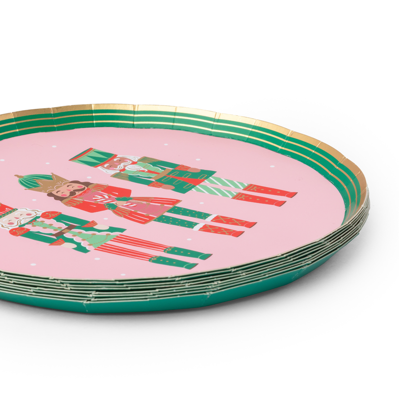 Angled stack of pink Nutcracker dessert plates showing the nutcracker figures, green-and-gold rim, and stack depth.