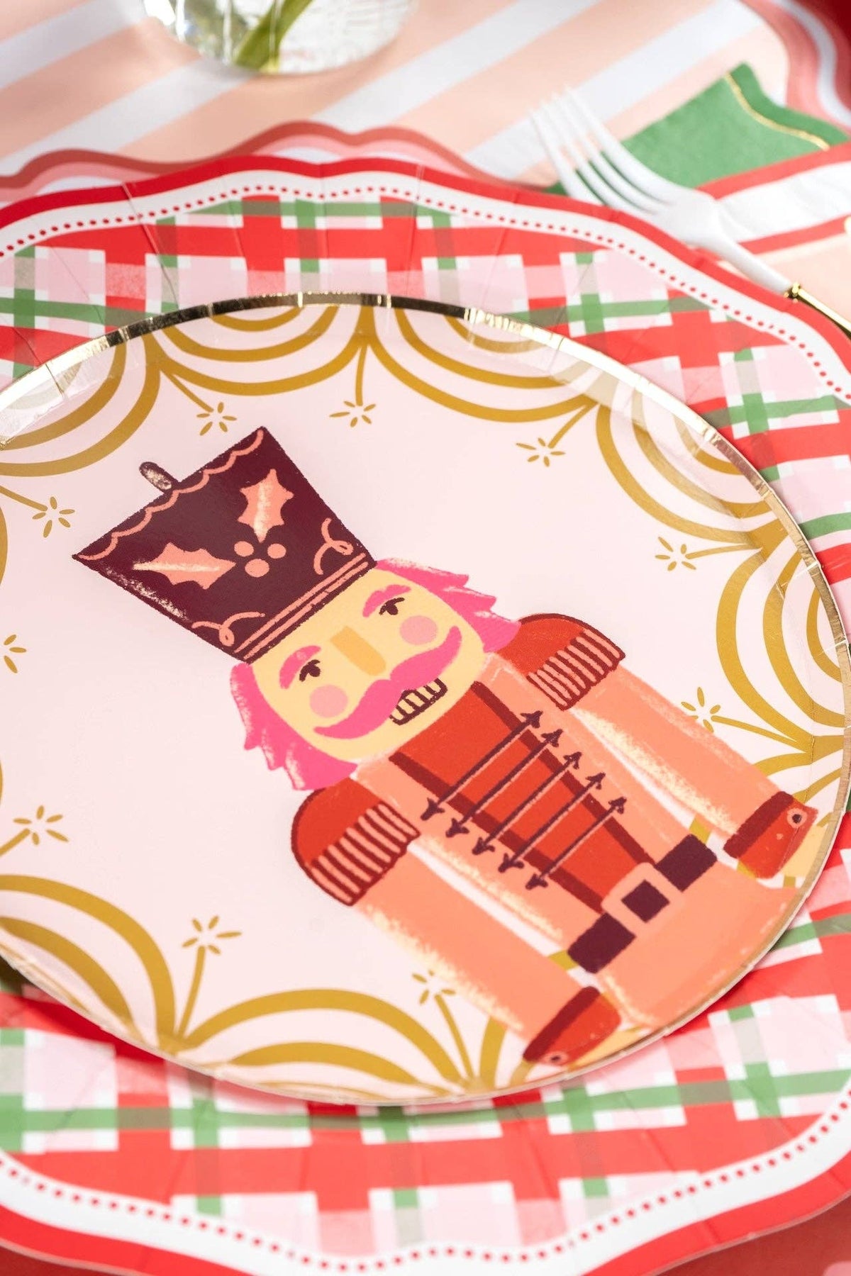 Close-up of a pink nutcracker plate layered on the plaid dinner plate.