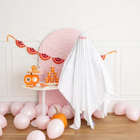 Banner strung across a pink spider-web backdrop with a child in a ghost costume.