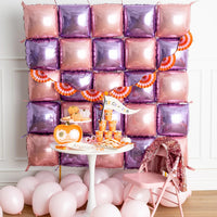 Wide shot of the balloon-wall party setup with the pink-and-orange fan banner across the top.