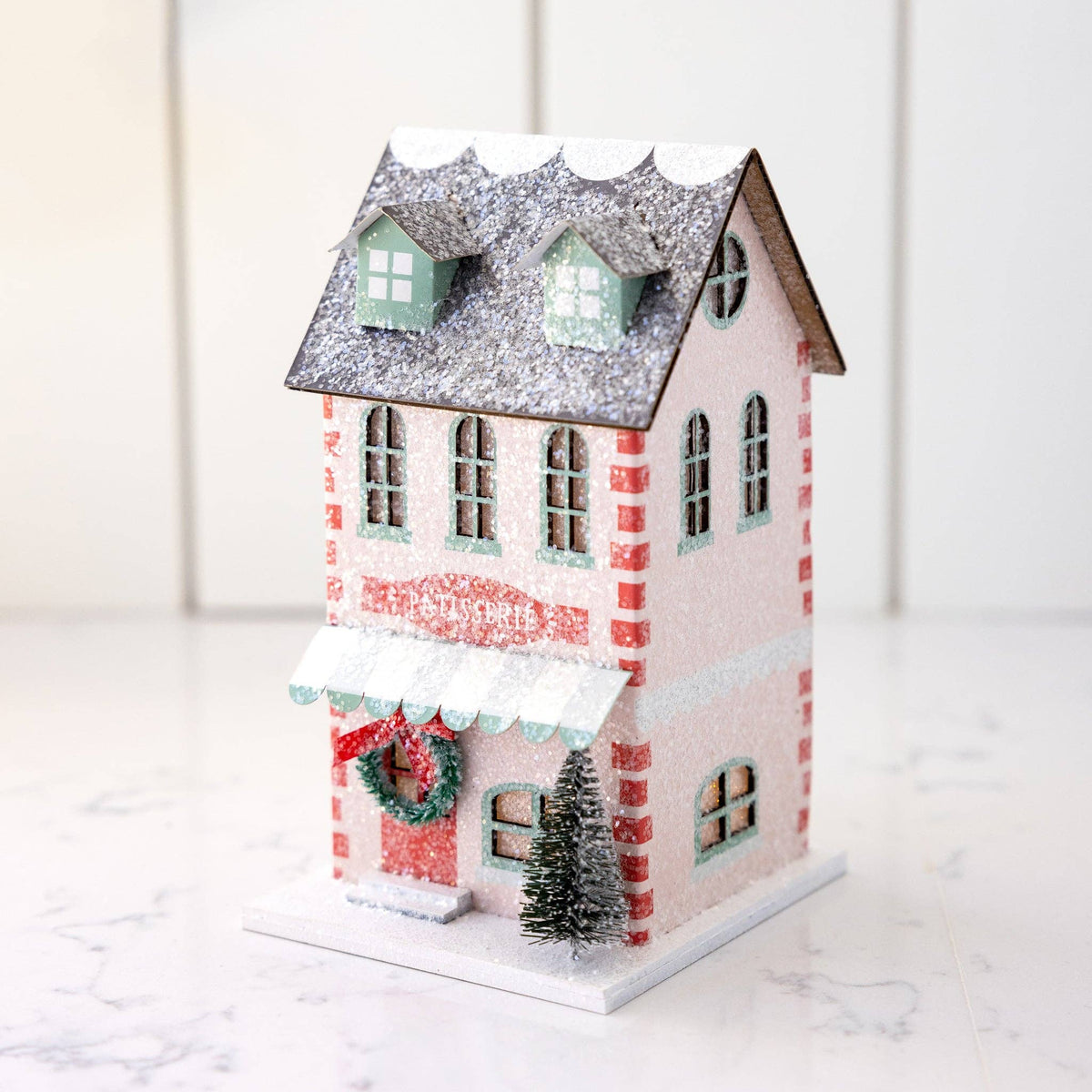 Angled view of the pink patisserie house on marble showing the side windows and dormered roof