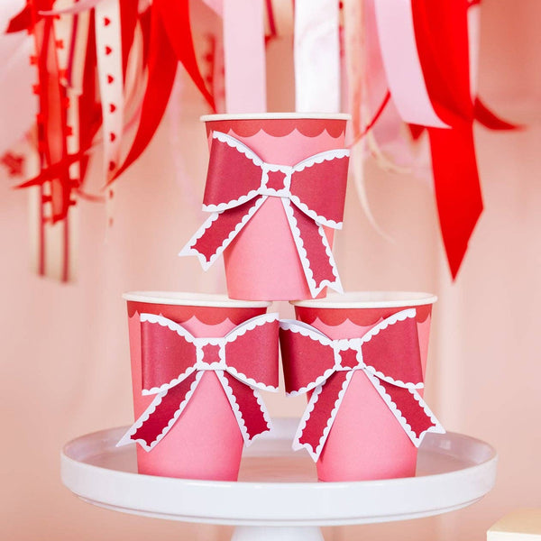 Valentine party table styled with pink and red bow paper cups