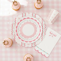 Overhead view of a coquette plate surrounded by crown cupcakes and ribbon napkins