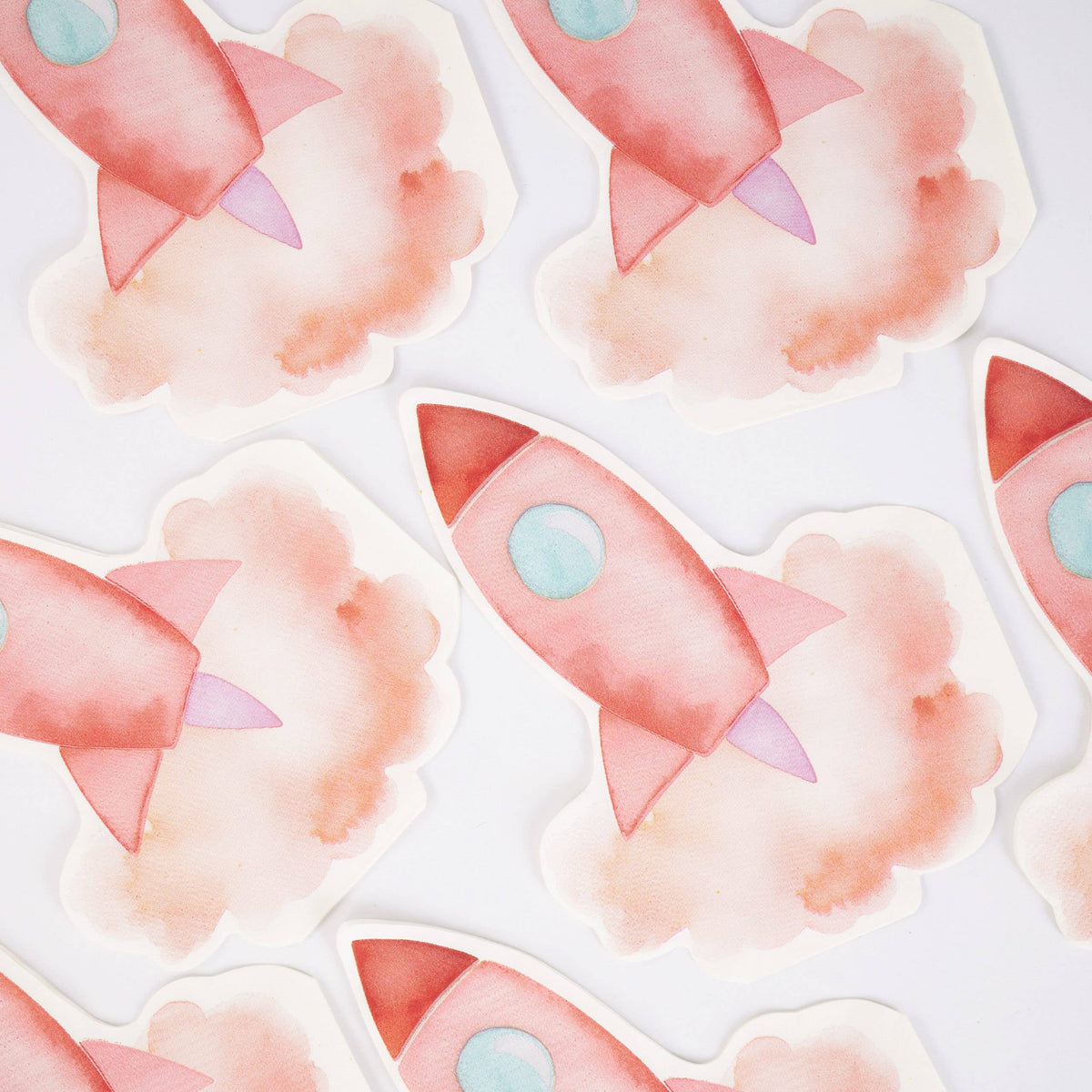 Group of coral pink rocket-shaped paper napkins arranged on white