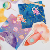 Pink space party spread with rocket napkins, galaxy napkins, planet plates and an astronaut cutout