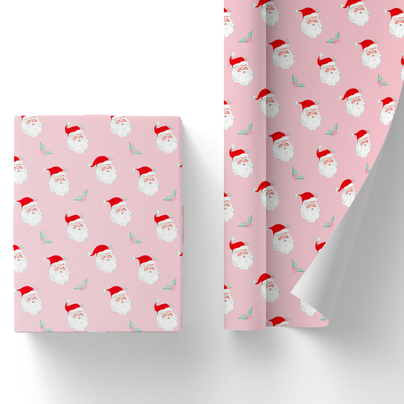 Wrapped gift box and partially unrolled pink Santa wrapping paper with a retro winking Santa and mint holly print