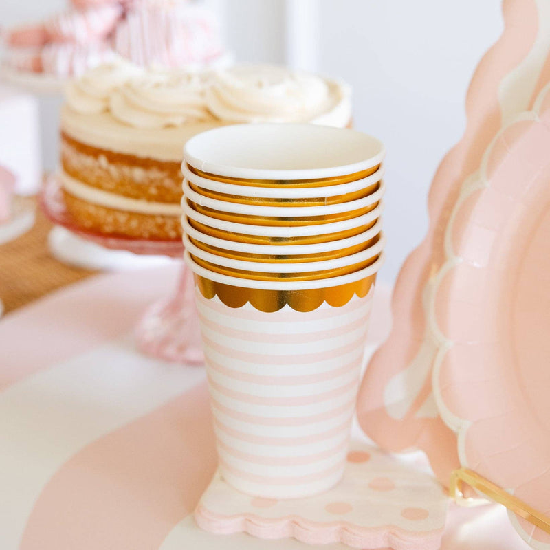 Stack of baby pink striped party cups styled on a dessert table
