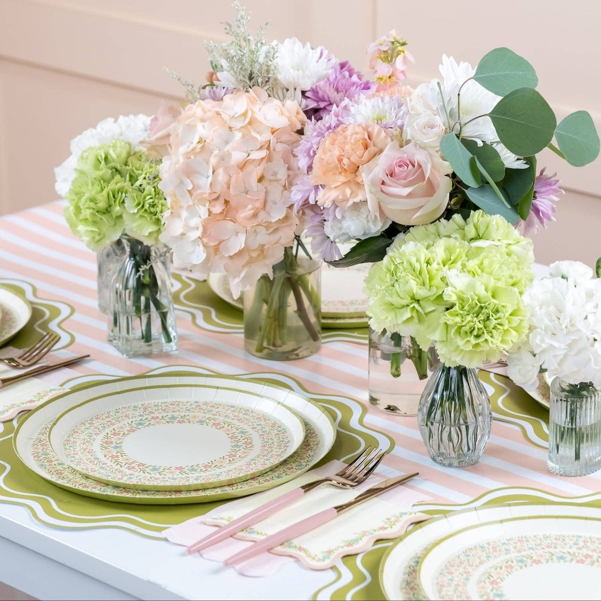 Pink striped table runner styled with pastel tableware and flowers