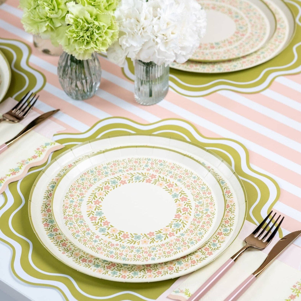 Pink striped table runner with green placemats and floral plate setting