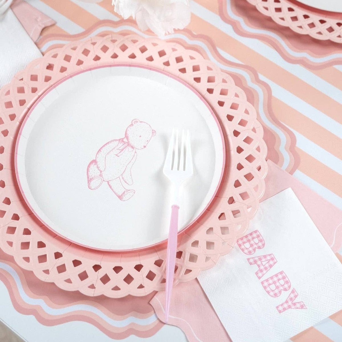 Pink teddy bear paper plate on a pink lattice charger with a pink handled fork and a pink gingham BABY napkin