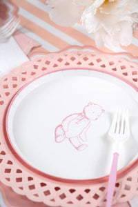 Pink teddy bear plate on a pink charger over a peach striped runner with white peonies