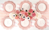 Six place settings with pink teddy bear plates, pink chargers, and a ranunculus and anemone centerpiece