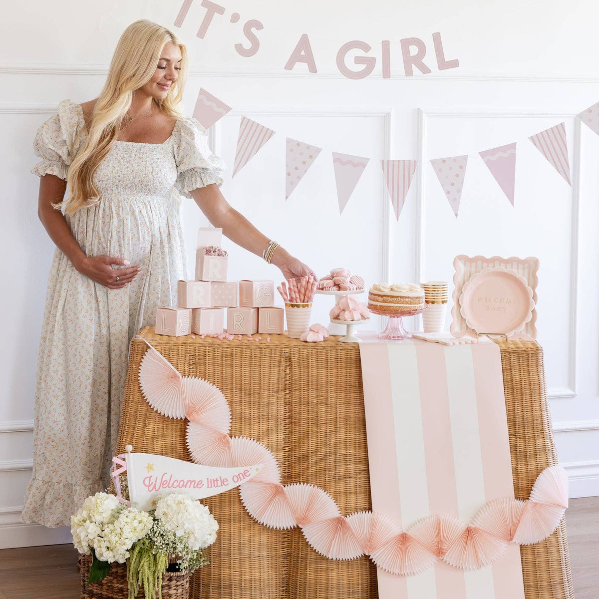 Pregnant mom next to baby shower table decorated with pink tissue bunting banner