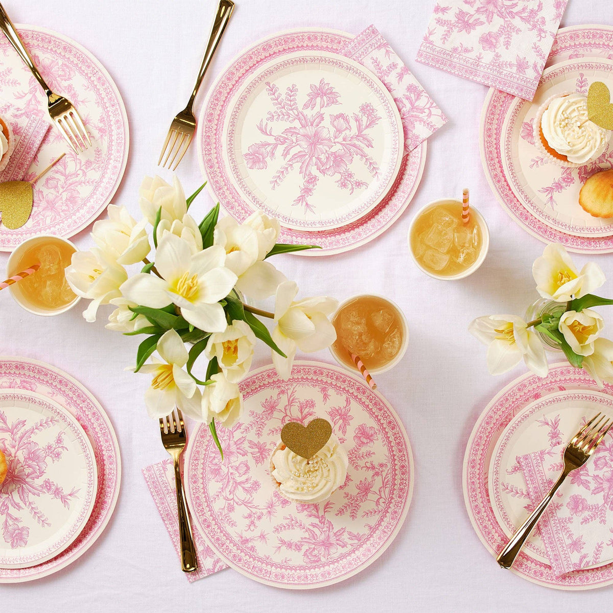 Overhead view of pink toile party table with floral arrangements.