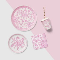 Pink toile plate with matching napkin and cup on styled background.