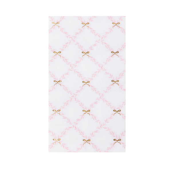 A folded white and pink trellis paper guest towel with small gold bow accents.