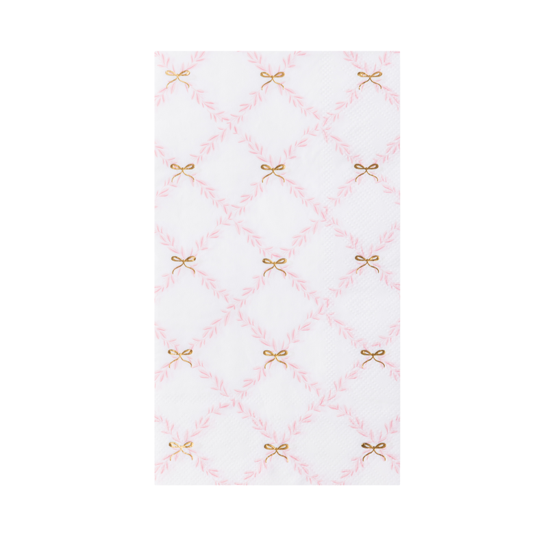 A folded white and pink trellis paper guest towel with small gold bow accents.