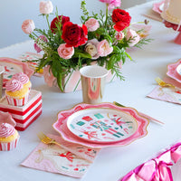 Table setting featuring pink Christmas decor plates, gold cups, and cupcakes, highlighting the ballet party supplies theme.