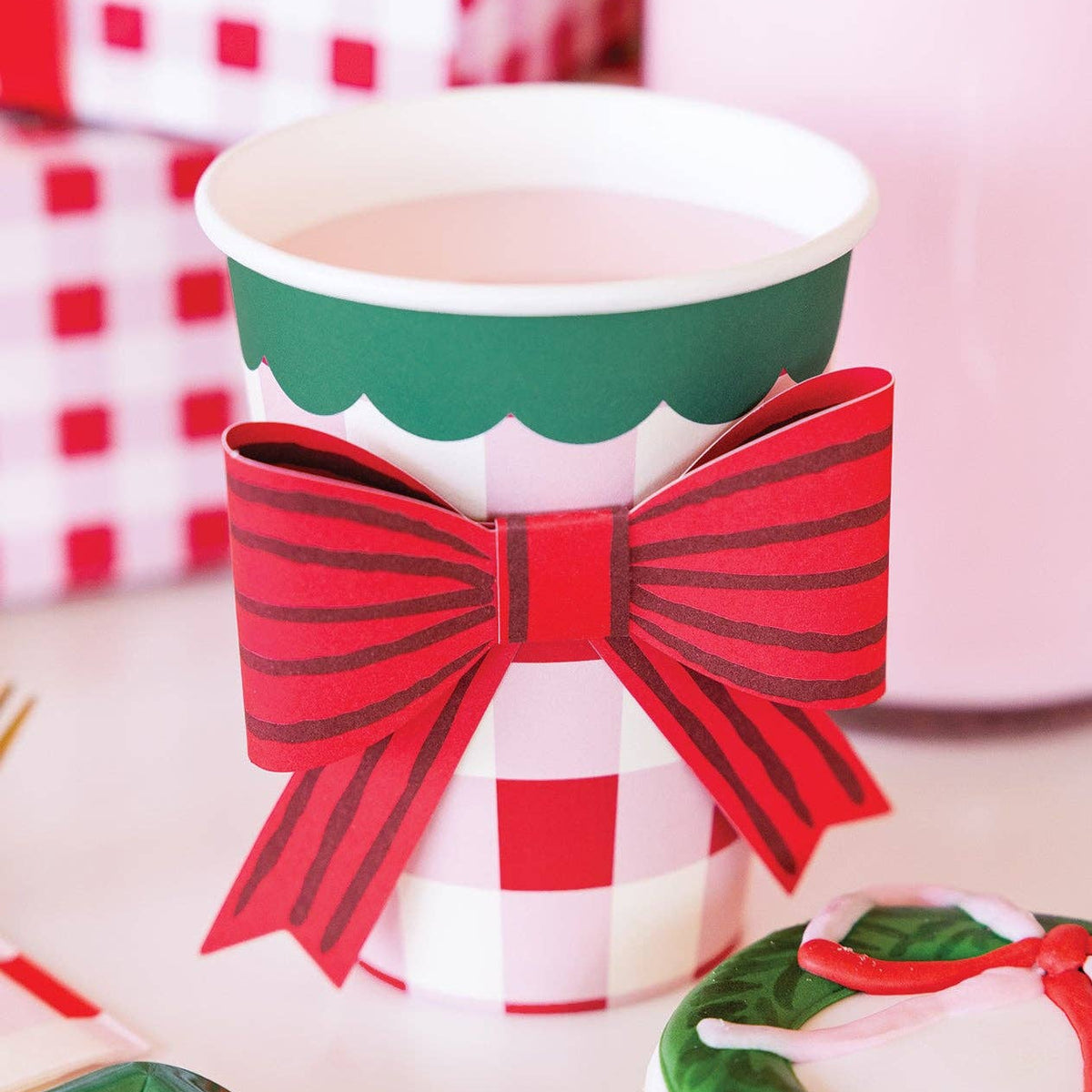 Closeup of plaid party cup with red bow on table with gifts and cookies