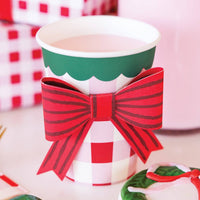 Closeup of plaid party cup with red bow on table with gifts and cookies