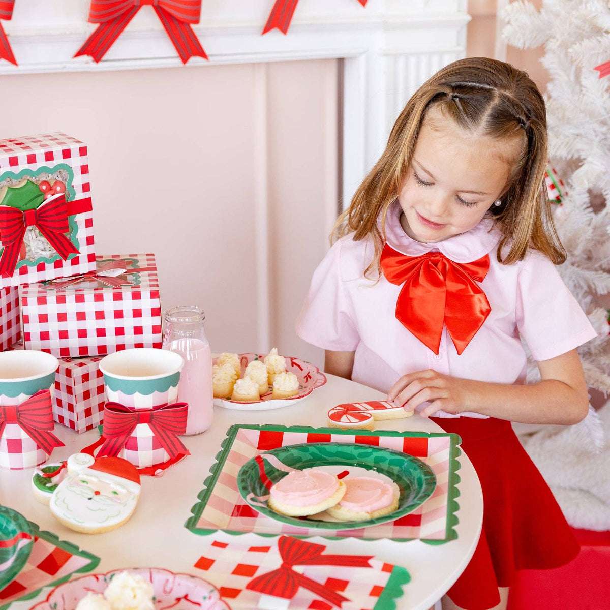 Girl enjoying cookies and milk at Christmas table with plaid decor